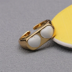 Detailed close-up of 18K gold star ring with double white enamel hearts and zircon accents