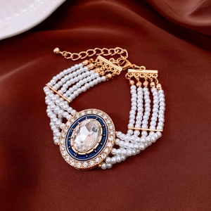 Detail of multi-layer pearl bracelet with blue enamel oval charm and crystal inlay