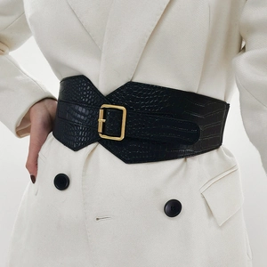Detail of wide black crocodile texture belt with gold buckle on a beige blazer