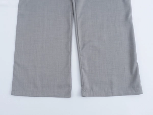 Vue détaillée de l'ourlet du pantalon gris montrant la texture précise du tissu de qualité