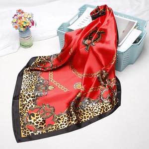 Macro detail of red leopard print satin scarf featuring vintage chain patterns and texture