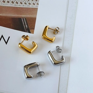 Detail of 14k gold and silver U-shaped chunky hoop earrings with polished finish