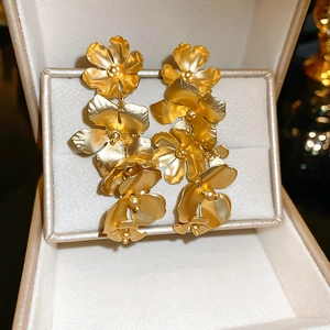 Détail de boucles d'oreilles fleurs en métal doré dans une boîte à bijoux de luxe