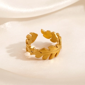 Golden stainless steel leaf ring with adjustable open design on cream silk fabric