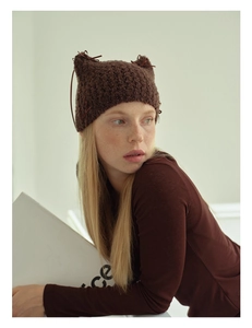 Detail of dark brown knit cat ear hat with textured yarn and cute bow tie strings
