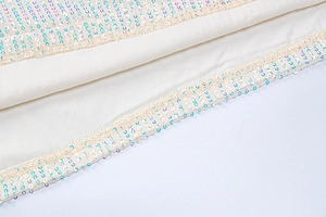 Detailed macro view of soft beige fabric featuring shimmering iridescent sequins decoration