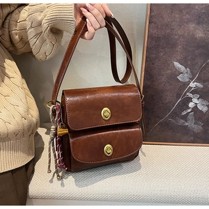 Detailed close-up of dark brown faux leather bag with double gold twist locks and woven knot