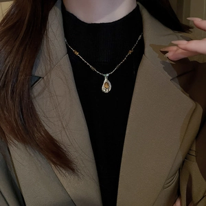 Détail macro du collier doré avec pendentif oeil de tigre sur blazer marron