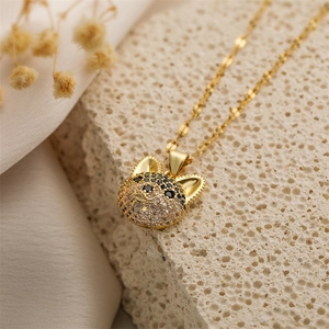 Close-up of a gold dog pendant necklace with clear and black stones on stone surface