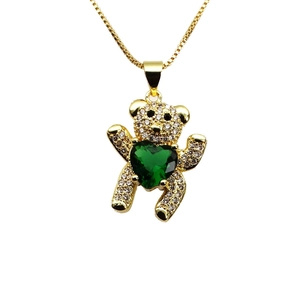 Macro shot of gold teddy bear pendant with micro-paved zircons and green heart gemstone