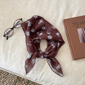 Close-up of floral linen scarf in dark brown and light blue on a textured surface