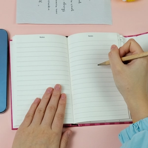 Detail eines rosa karierten Notizbuchs mit linierten Seiten und Notes-Header im Lifestyle