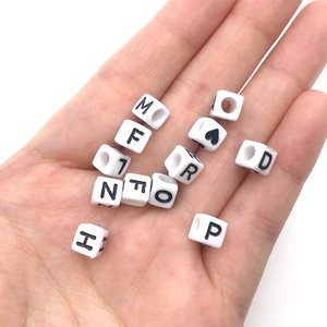 Close-up of white acrylic letter beads held in palm for DIY jewelry making