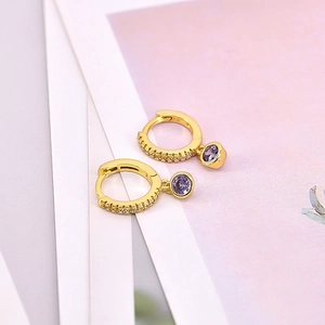 Detail of gold-plated hoop earrings featuring a round purple zircon and pave white stones
