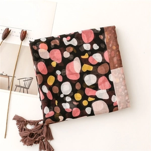 Detail of colorful polka dot cotton scarf with brown tassels on a white background