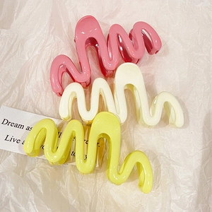 Three wavy hair claws in pastel pink, cream, and yellow colors for back of head styling