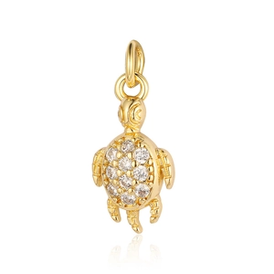 Macro detail of a golden turtle pendant with sparkling cubic zirconia on white background