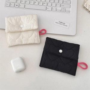 Close-up of heart-quilted cotton pouches in cream and black with button closure