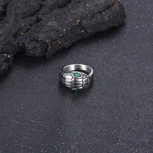 Detail of 316L stainless steel snake ring with green gem eyes on black sand
