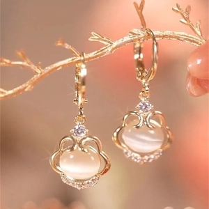 Detailed close-up of golden Ruyi lock earrings with opal stones on elegant dry branches