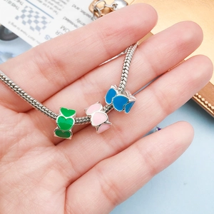 Close-up of silver snake chain bracelet featuring colorful enamel heart charms