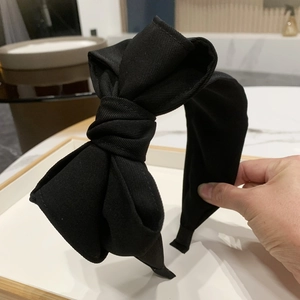 Detail of multi-layered black bow headband with elegant pleated texture and wide band
