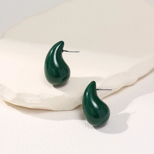 Detailed close-up of dark green teardrop stud earrings on a textured stone base