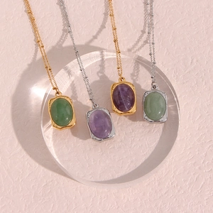 Detailed view of oval natural stone pendants with gold and silver chains on acrylic bases