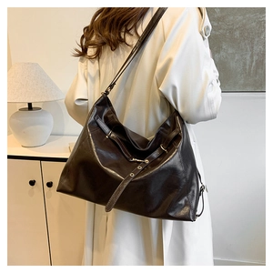 Detail of dark brown glossy leather tote bag shown on a model in a modern home setting