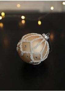 Close-up of champagne gold satin Christmas ball with white beads and crystal rhinestones