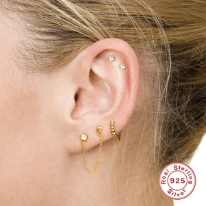 Macro shot of gold 925 sterling silver tassel chain earrings with zircon studs on ear
