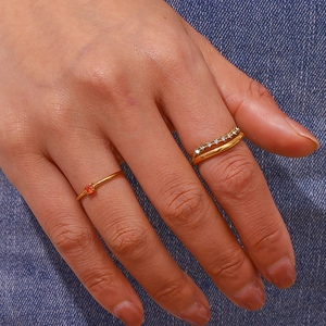 Detail von goldfarbenen Doppelringen mit orangefarbenem Edelstein und Zirkonia-Akzenten
