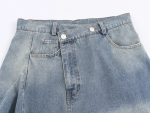 Close-up of light blue denim midi skirt with asymmetrical double-button waist design