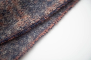 Detail of blue and orange jacquard weave scarf featuring soft texture and blue stitched edges