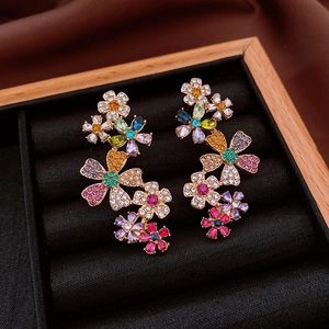 Detail of 18k gold plated flower earrings with multi-color zircons on black velvet