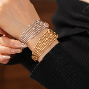 Détail de bracelets perlés dorés et argentés sur mannequin montrant la texture métal