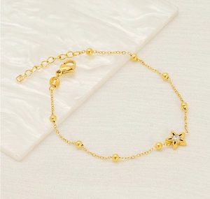 Macro shot of gold bead chain bracelet featuring a star charm with zircon stone
