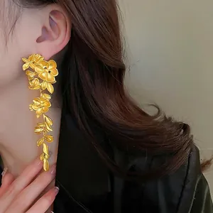 Elegant gold flower and leaf tassel earrings worn by model for high-end fashion look