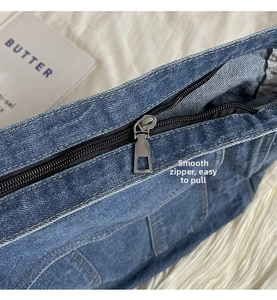 Détail de la fermeture éclair en métal lisse sur un sac bandoulière en denim bleu
