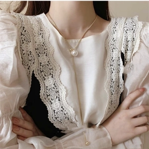 Elegant gold long Y-necklace with white pearl pendant on a lace dress background