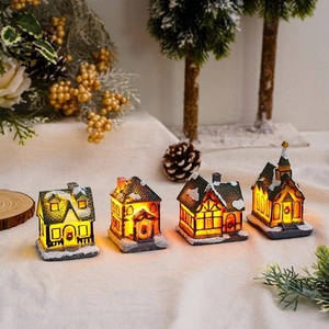 Set of four glowing resin Christmas village houses with snowy roofs and warm LED light effect