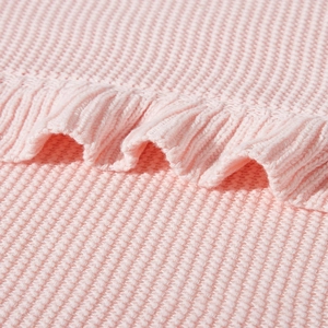 Close-up of pink knitted baby blanket featuring soft ruffle edges and waffle texture