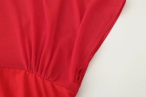 Detail of red mesh fabric showing refined stitching and pleated textures on the dress