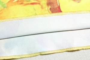 Detailed macro view showing the yellow floral print fabric and precise overlock stitch