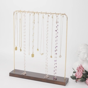 Golden necklace display stand with 12 hooks and dark brown wooden base on white background
