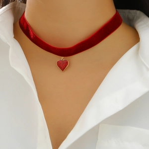 Close-up of red velvet choker necklace with sparkling heart pendant on a white shirt