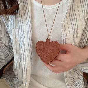 Close-up of caramel leather heart pendant with lychee texture and fine stitching detail