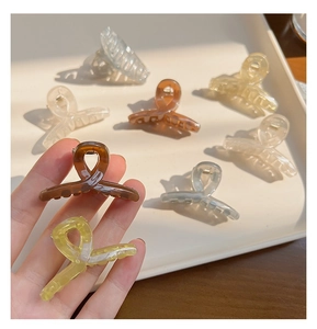 Detail of 4.5cm translucent jelly shark hair clips in amber and yellow on a white tray