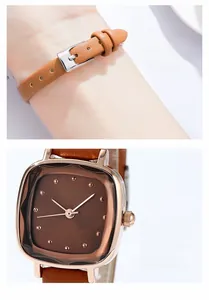 Detail view of square rose gold watch case with brown leather strap and pin buckle