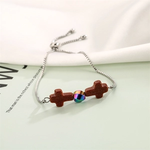 Detail of adjustable silver chain bracelet with brown stone crosses and iridescent bead